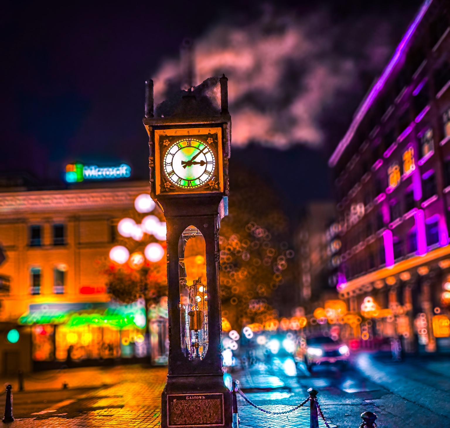 Illuminated steam clock surrounded by colorful city lights and drifting steam