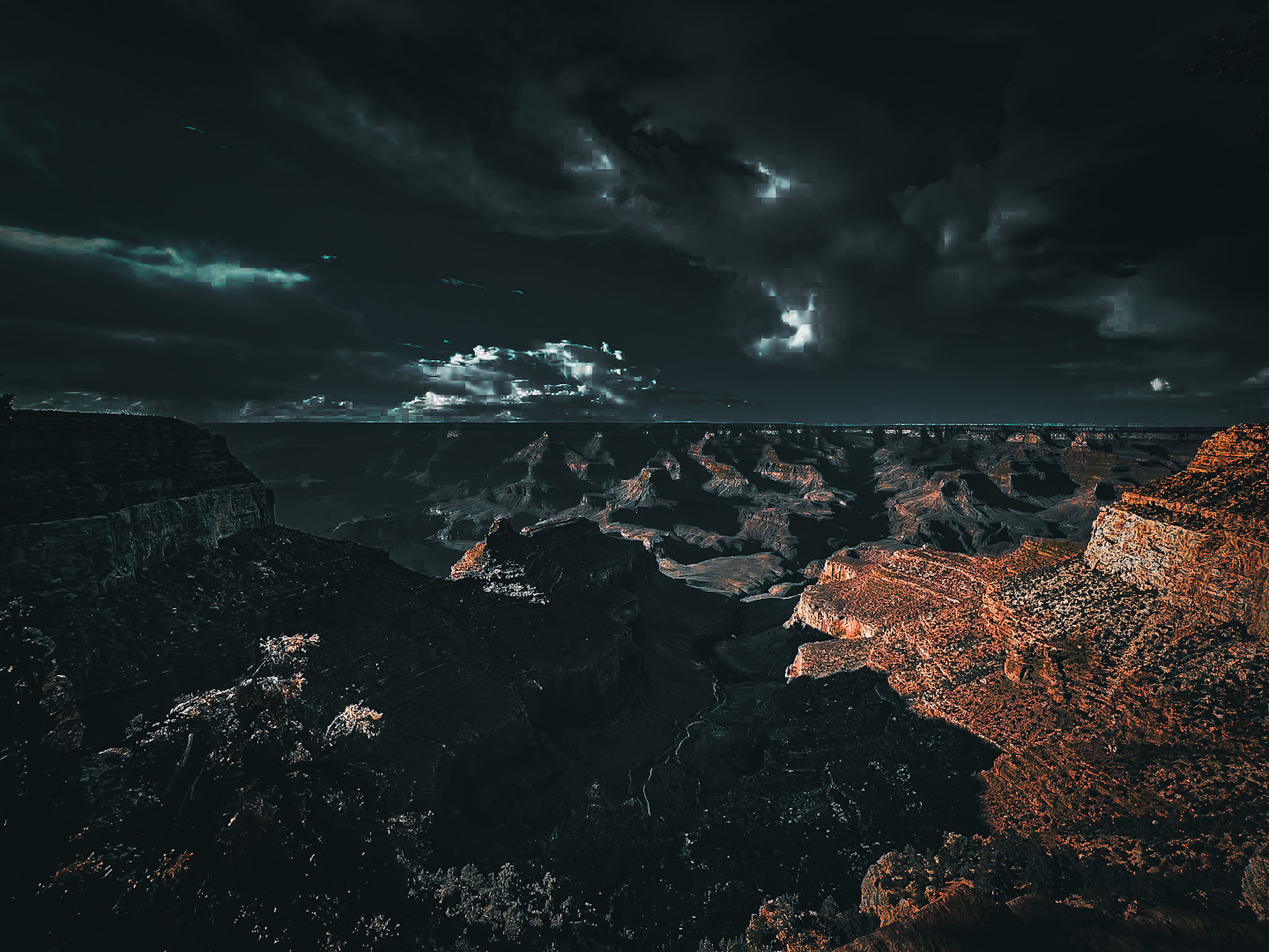 Sunlight crossing a rugged canyon beneath dark storm clouds