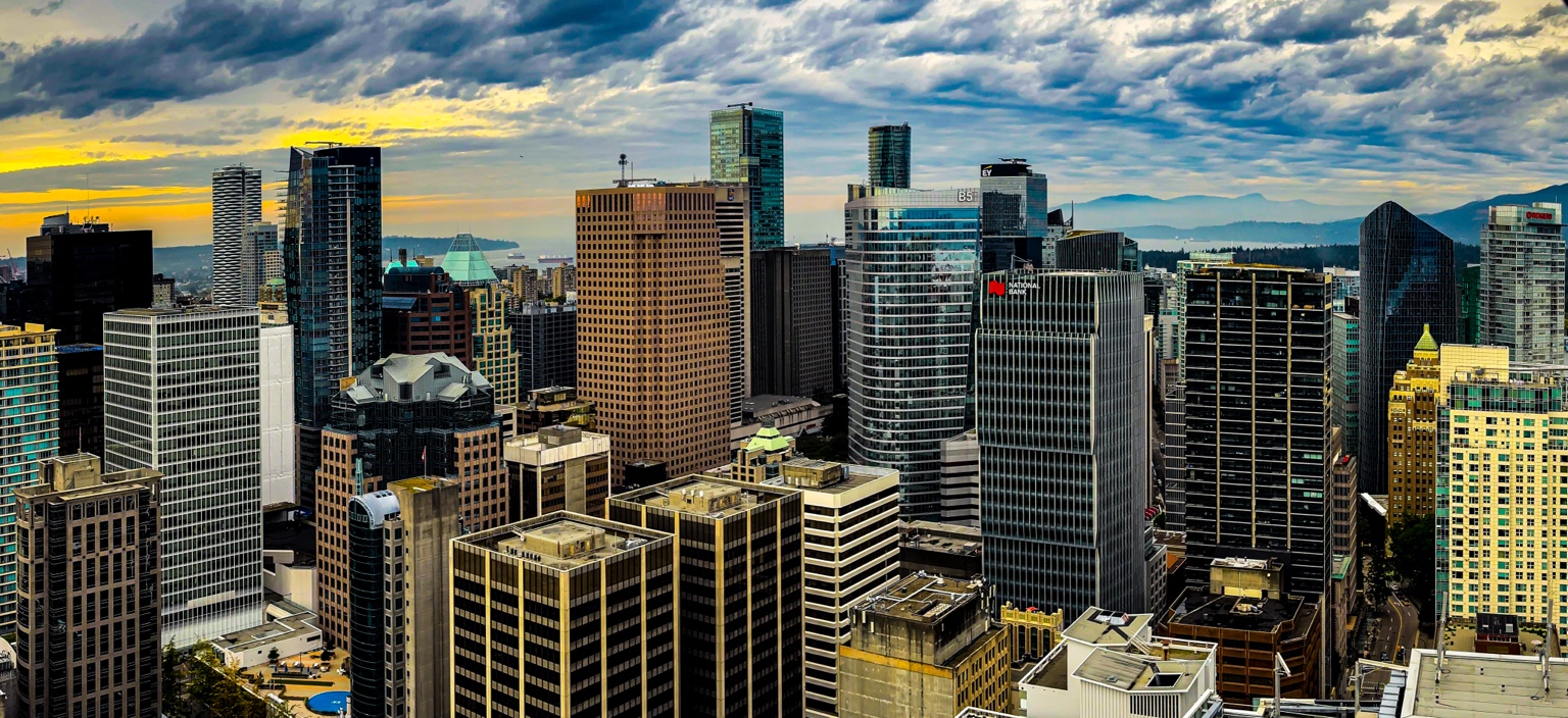 Downtown towers beneath textured clouds with distant hills and water