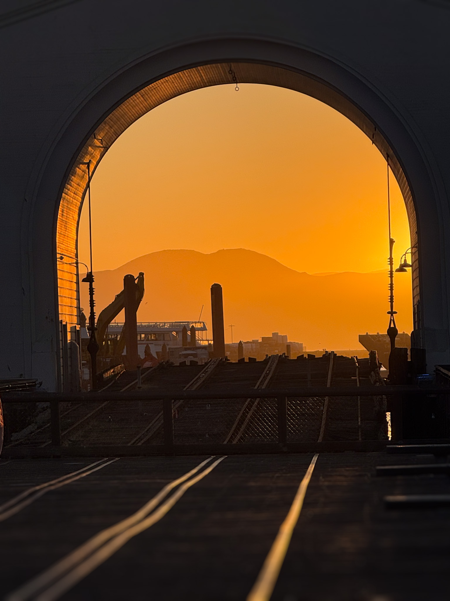 Industrial archway framing a golden mountain sunset