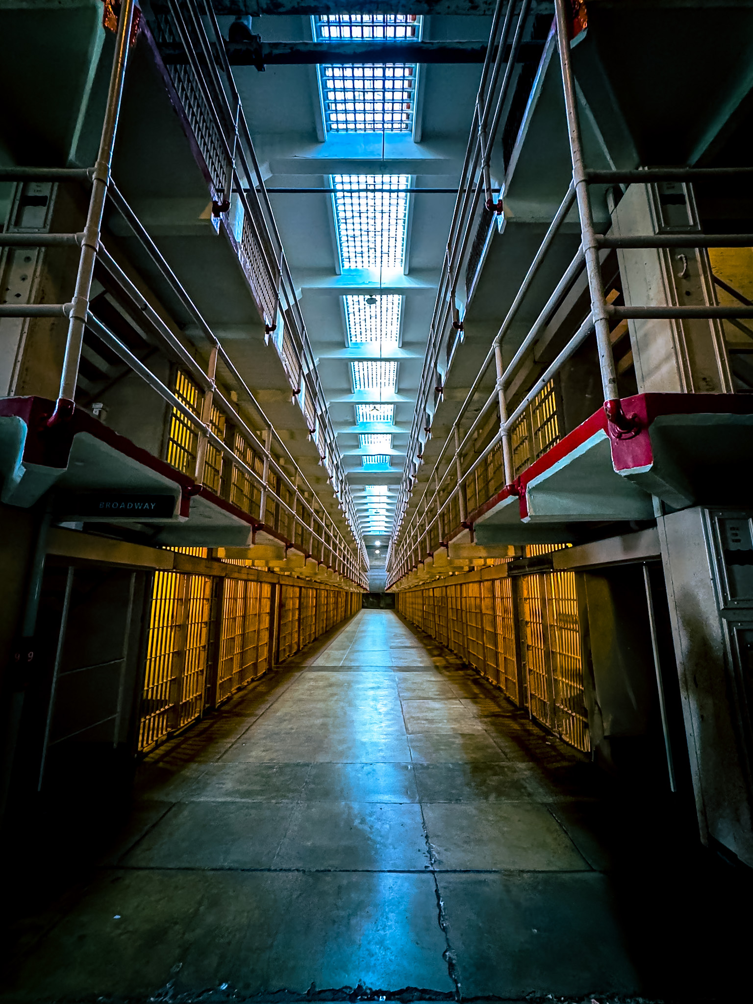 Symmetrical prison corridor illuminated in blue and amber